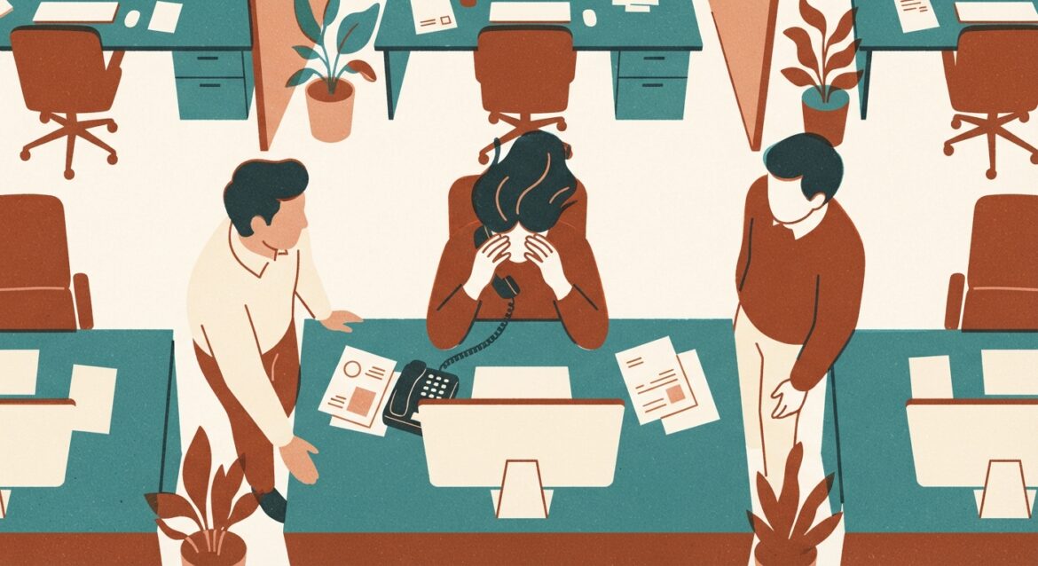 A stressed office worker covering a phone receiver at their desk while coworkers look over