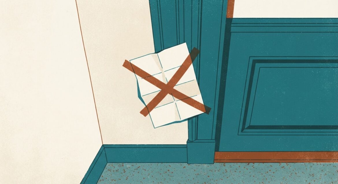 A folded legal notice taped to an apartment door frame